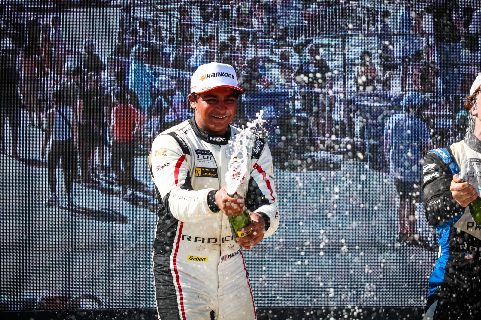 Valen Venkatesh spraying champagne on the podium at Road America